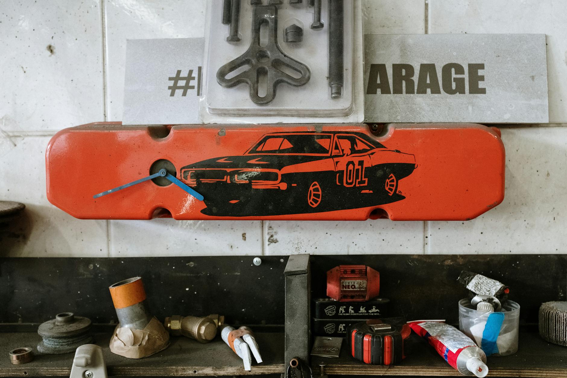 Czerwony element auta z zegarem na ścianie garażu wśród narzędzi