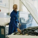 Mechanik w niebieskim kombinezonie sprawdza silnik Iveco w warsztacie