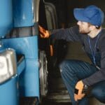 Mechanik w warsztacie sprawdza koło niebieskiej ciężarówki Iveco