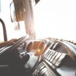 Kierowca autobusu prowadzący pojazd po ulicach miasta w słoneczny dzień